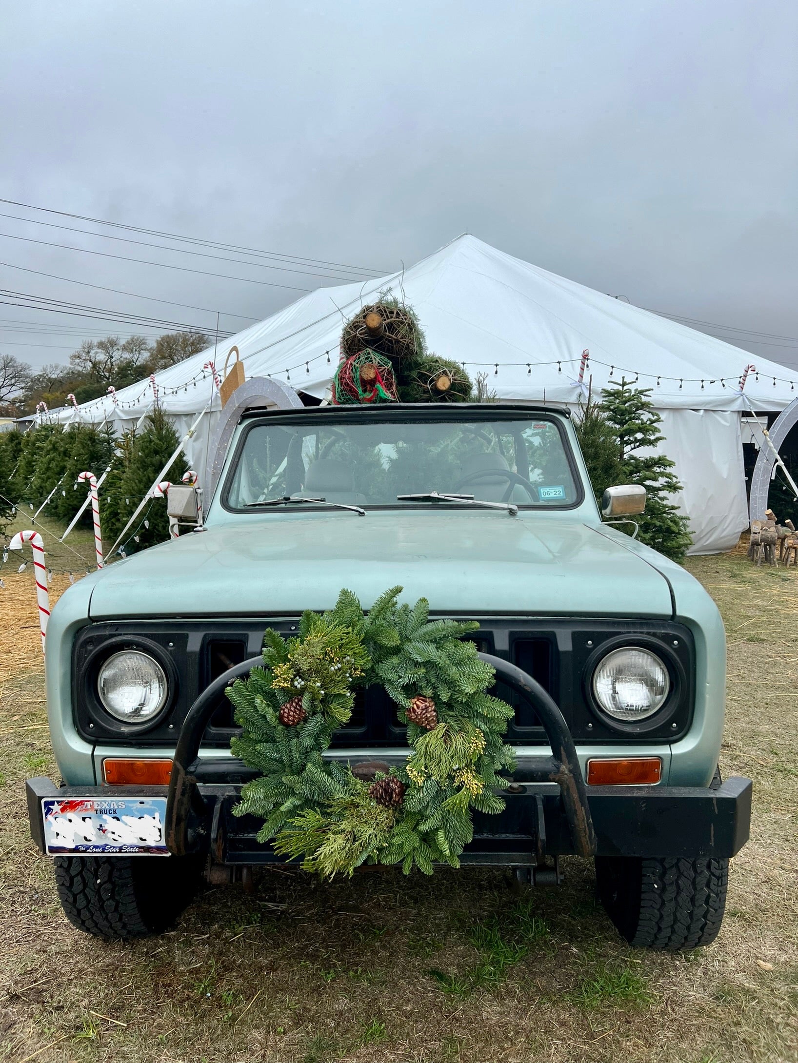 The lot truck with a fresh wreath on the grille and a tree on the roof, Dripping Springs.